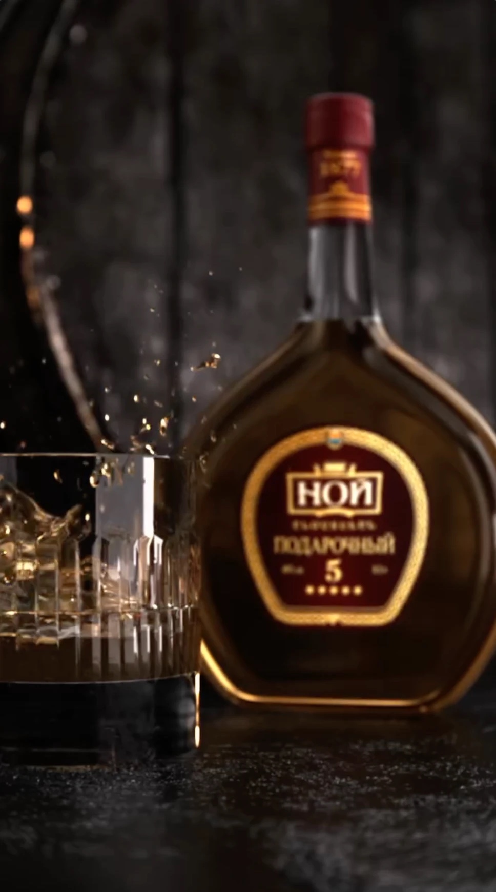 Whiskey glass with splash next to a bottle, spec-ad scene