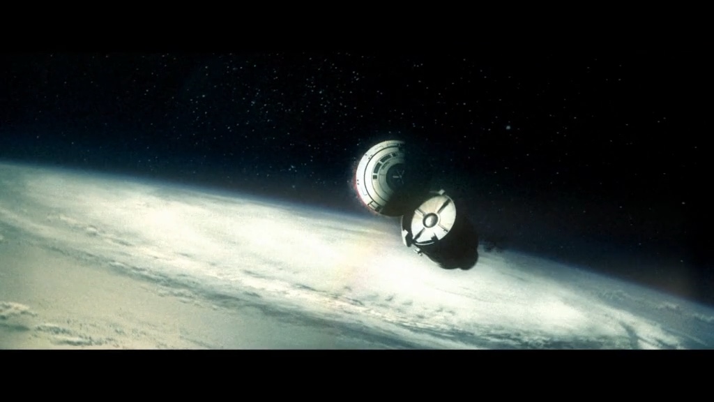 Space capsule in orbit above Earth, with the cloud cover below